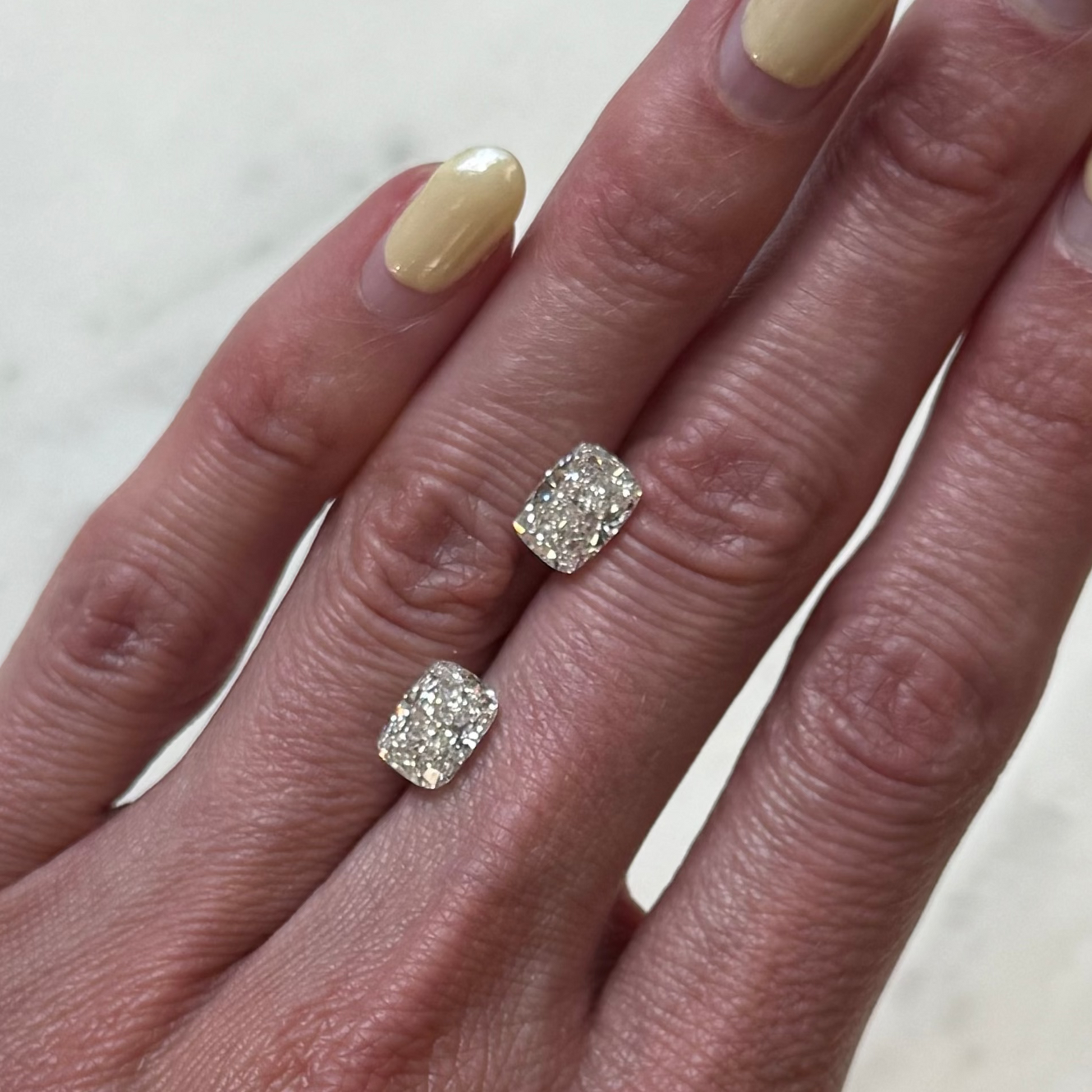 Hand with two diamond rings on a marble surface